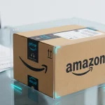 Коробка доставки Amazon на скляному столі поруч із суддівським молотком як символ колективного позову