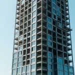 Framework of a modern modular skyscraper made of steel structures during assembly against a clear blue sky